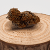 Fleur de CBD WEDDING CAKE cultivée en Greenhouse, posée sur une rondelle de bois. Fleur de chanvre naturelle avec THC < 0,3%.