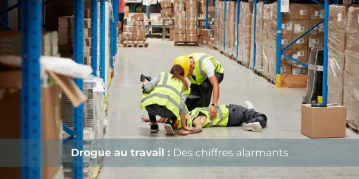 Texte alternatif :Employé effondré dans un entrepôt, collègues en gilets jaunes portant secours.