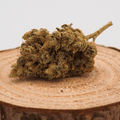 Fleur de CBD ALIEN HAZE cultivée en indoor, posée sur une tranche de bois. Fleur de chanvre 100% bio avec THC inférieur à 0,3%.