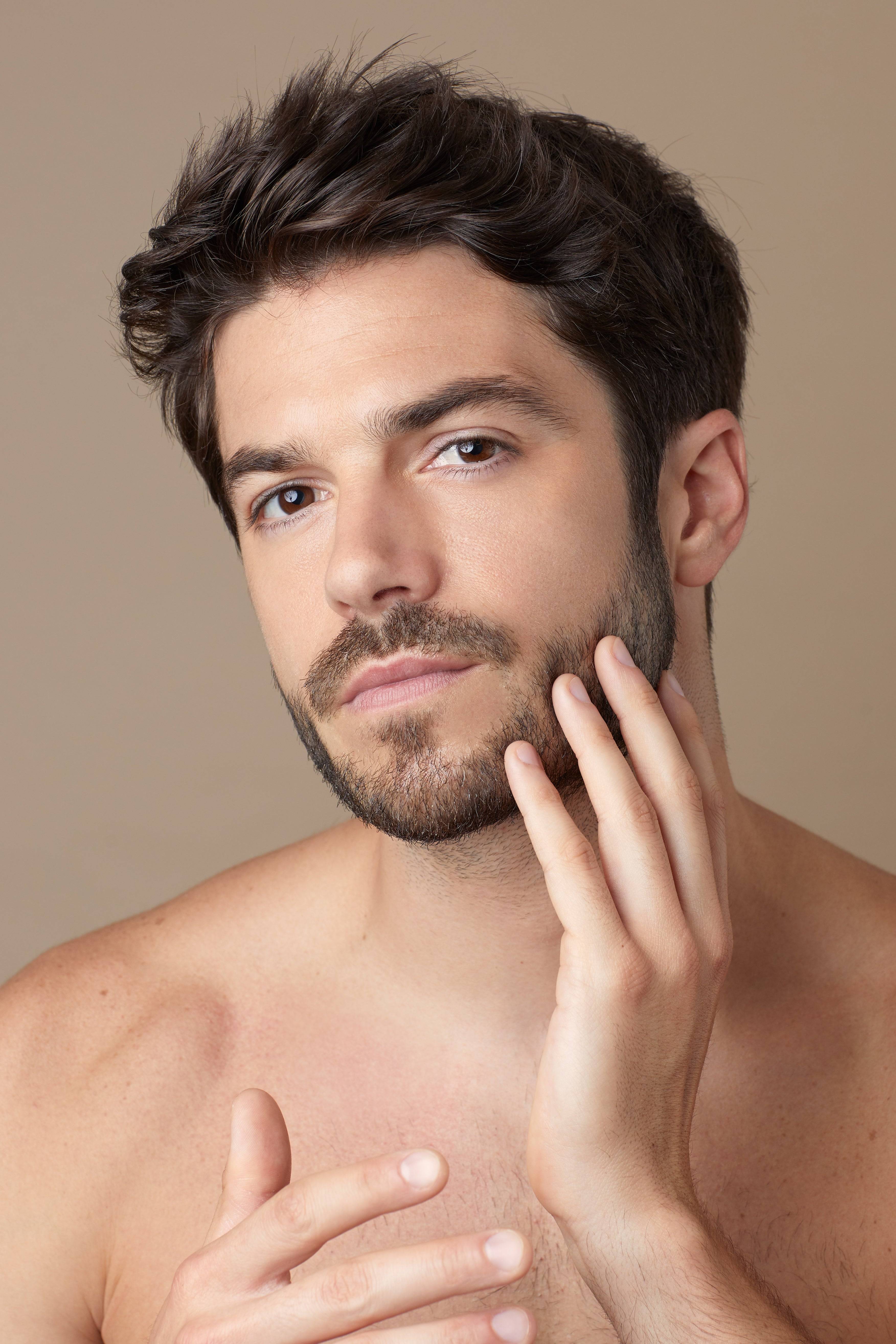 Homme appliquant HUILE STUPÉFIANTE HO KARAN sur son visage, soin hydratant au CBD pour visage, corps et cheveux, idéal pour une routine beauté naturelle.