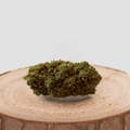 Fleur de CBD ORANGE STICKY cultivée en Greenhouse, posée sur une tranche de bois. Produit naturel avec THC inférieur à 0,3%.